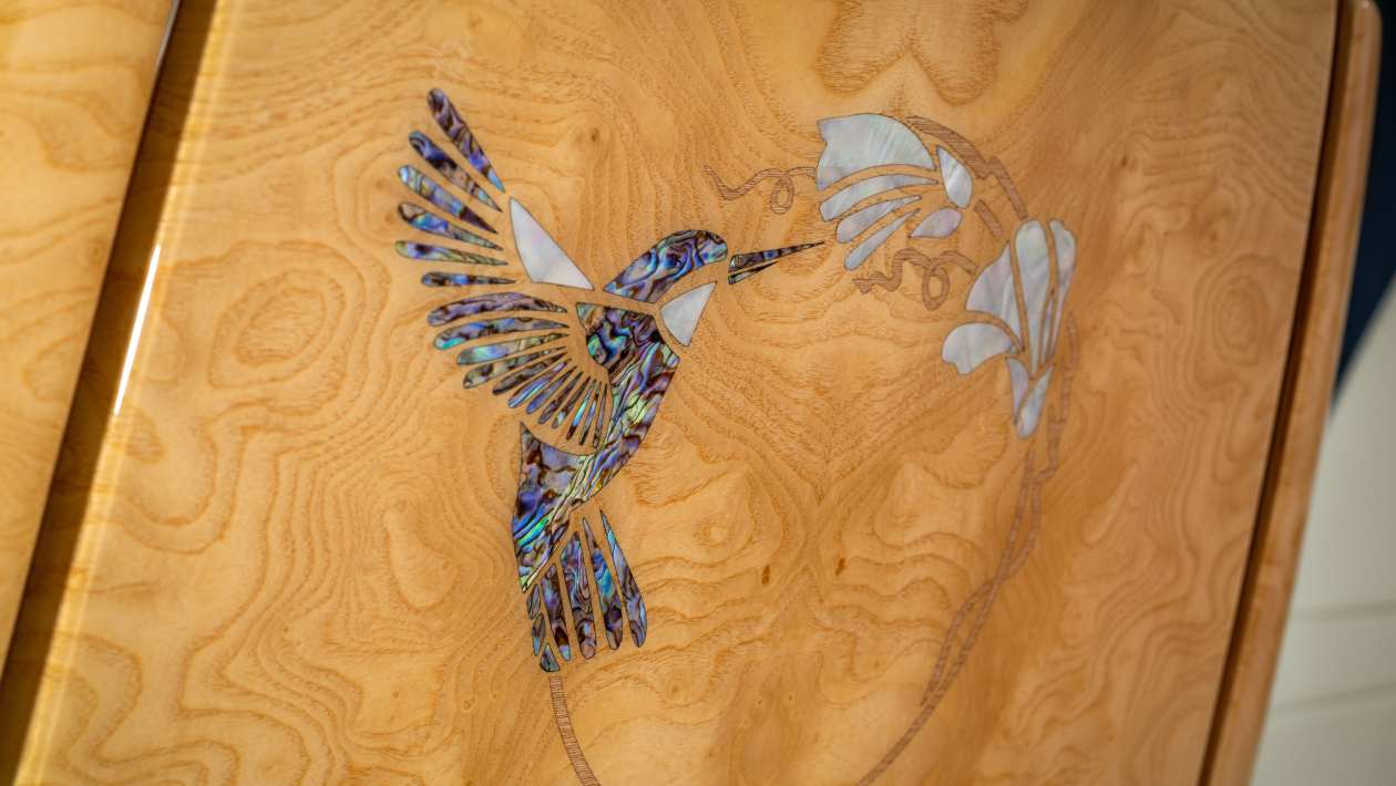 Pasăre colibri realizată din fragmente de abalone și sidef pe un panou din lemn